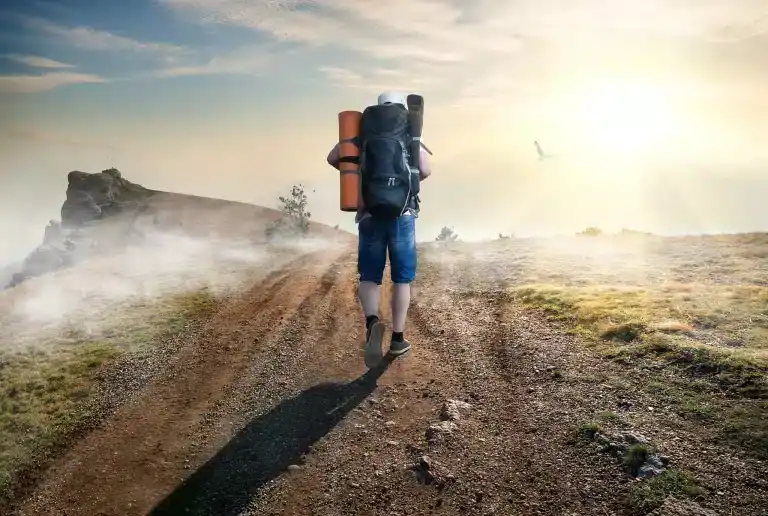 Hiker walking on trail toward sunrise, peace and hope, spiritual journey, reclaiming shalom.