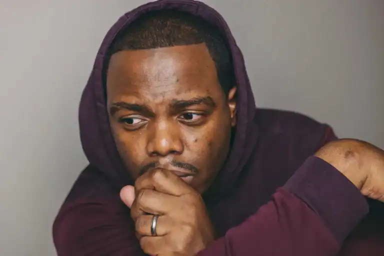 A man sitting quietly in deep thought, feeling overwhelmed and exhausted.