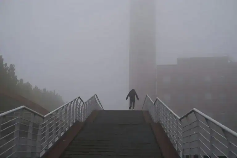 Person walking up stairs through fog, facing a decision