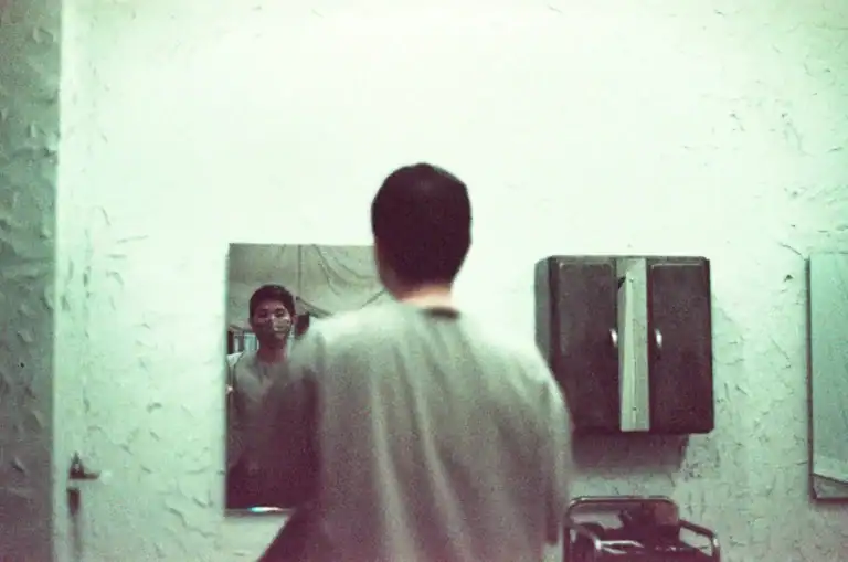 Man standing in front of a mirror in quiet reflection
