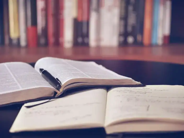 Books and study materials on a desk with warm lamp light