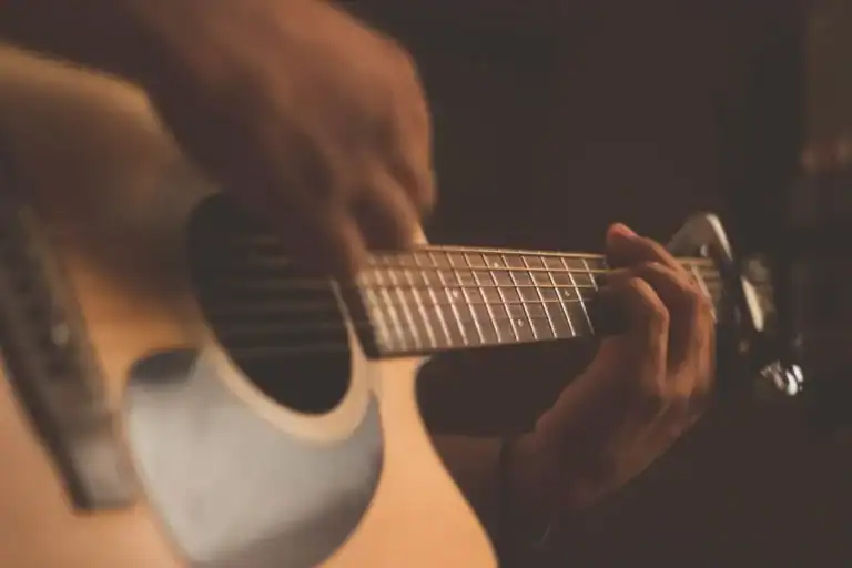 Close-up of guitar strings and hands, evoking the tension of music practice