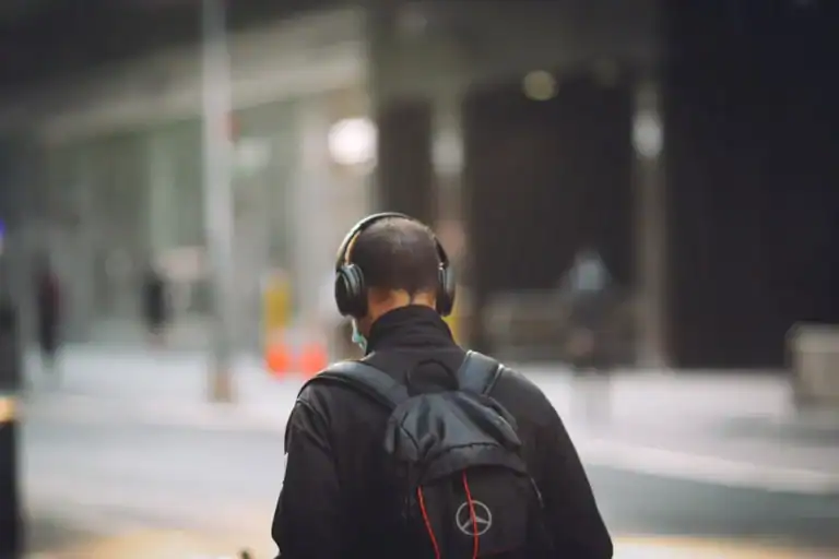 Man in black jacket wearing headphones, walking in solitude