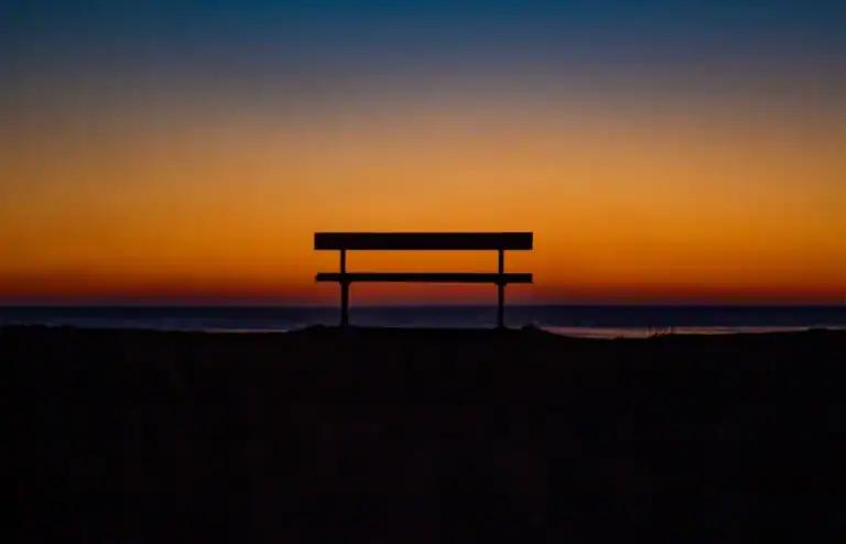 Empty bench near the shoreline at sunset, a quiet place for reflection